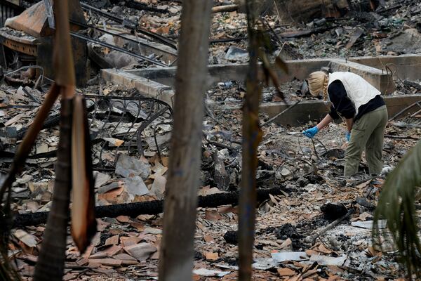 A resident sifts through their fire-damage property after the Franklin Fire swept through, Wednesday, Dec. 11, 2024, in Malibu, Calif. (AP Photo/Damian Dovarganes)