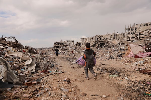 A Palestinian boy carries his belongings as he walks with his family next to the rubble of destroyed homes, after the ceasefire deal between Israel and Hamas, in Gaza City, Gaza Strip, Friday, Jan. 24, 2025. (AP Photo/Abed Hajjar)