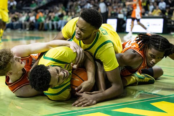 Oregon guard Ra'Heim Moss (0) grimaces as Oregon forward Kwame Evans Jr. lands hard. Illinois guard Kasparas Jakucionis and forward Morez Johnson Jr., right, go for the ball during the second half of an NCAA college basketball game in Eugene, Ore., Thursday, Jan. 2, 2025. (AP Photo/Thomas Boyd)