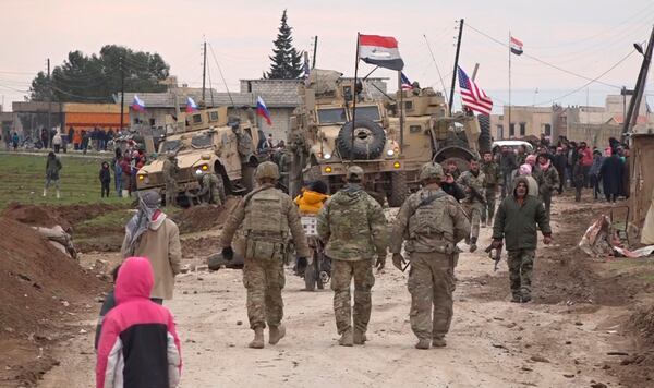 FILE - In this frame grab from video, Russian, Syrian and others gather next to an American military convoy stuck in the village of Khirbet Ammu, east of Qamishli city, Syria, Feb. 12, 2020. (AP Photo, File)