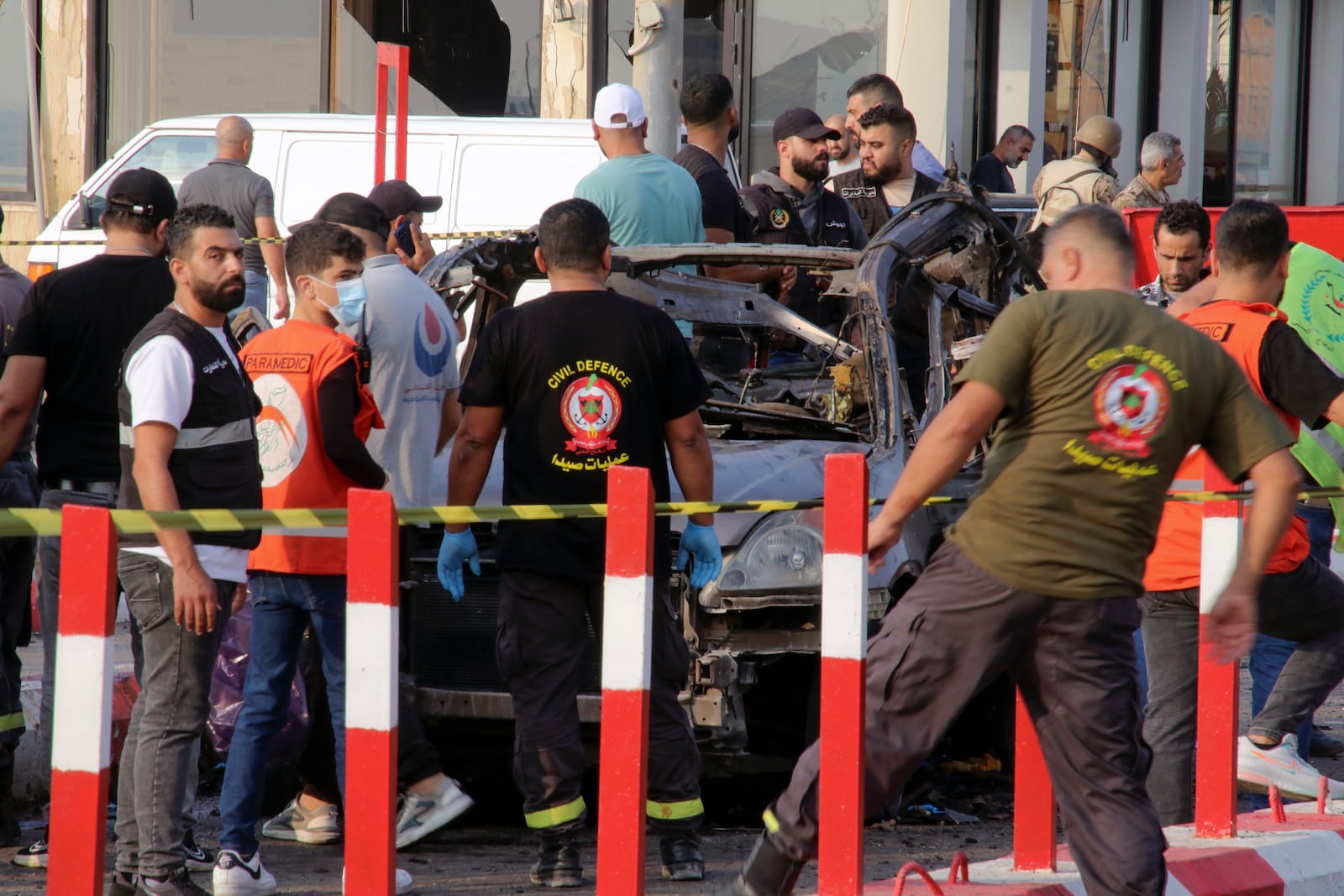 In this handout photo, civil defense workers and paramedics stand next to a charred car in an Israeli airstrike at the entrance of the southern port city of Sidon, Lebanon, Thursday, Nov. 7, 2024. (AP Photo)