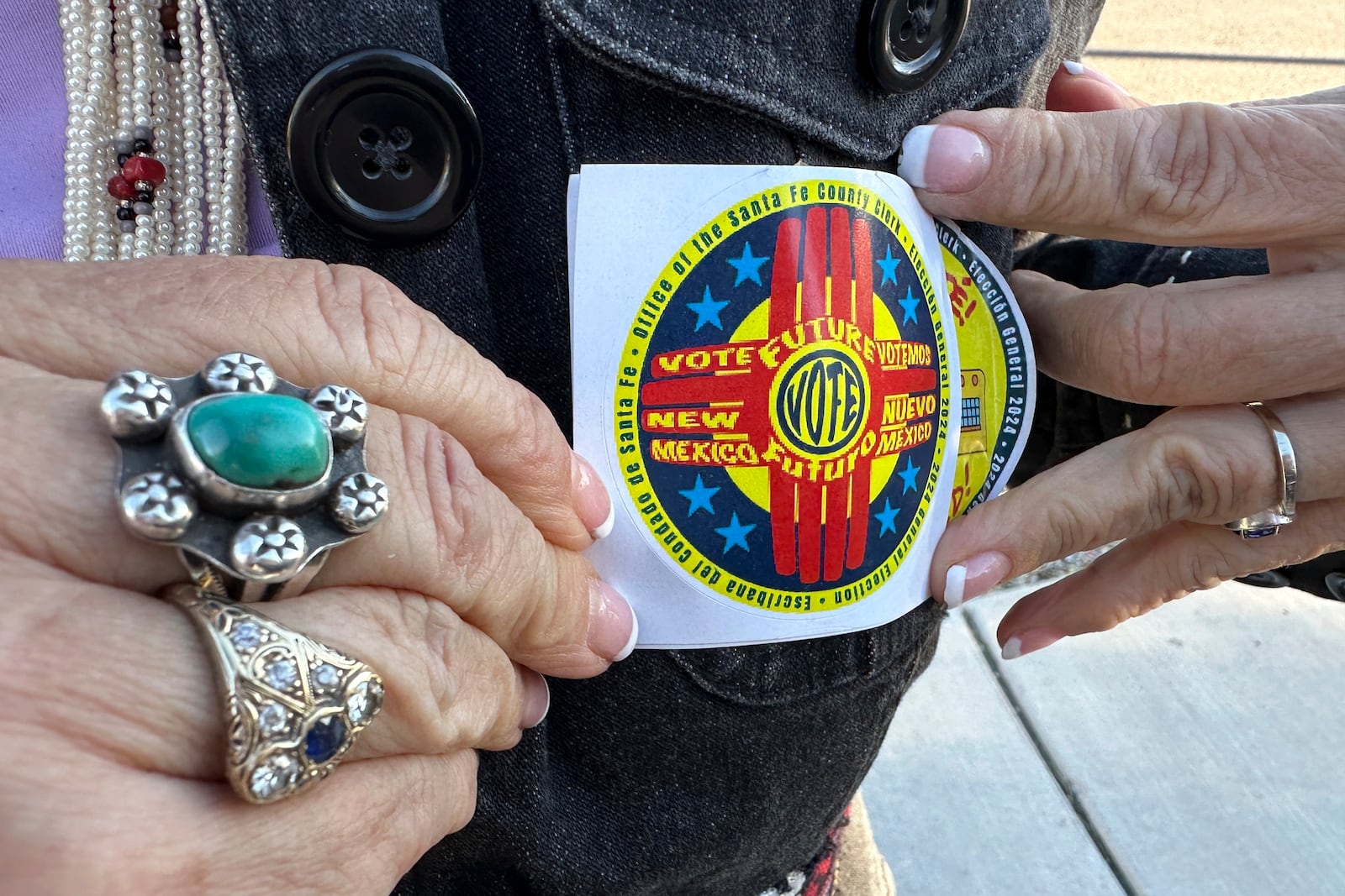 U.S. Rep. Teresa Leger Fernández holds up a voting sticker as she campaigns for fellow Democrats in Albuquerque, N.M., on Wednesday, Oct. 30, 2024. (AP Photo/Susan Montoya Bryan)