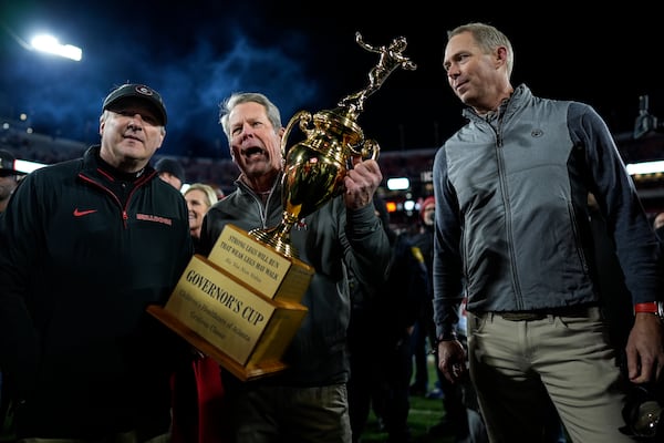 Georgia Gov. Brian Kemp, center presents the Governor's Cup to Georgia head coach Kirby Smart after an eight overtime NCAA college football game against Georgia Tech, Saturday, Nov. 30, 2024, in Athens, Ga. Georgia won. (AP Photo/Mike Stewart)