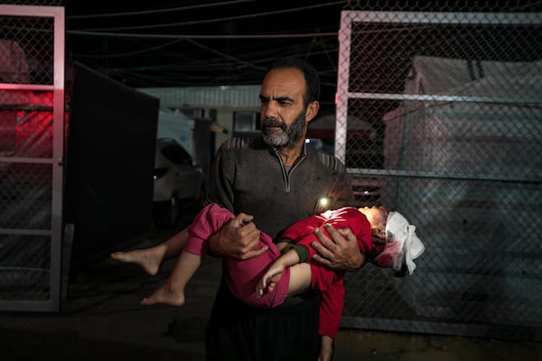 A Palestinian man carries a wounded girl, following an Israeli bombardment on the Gaza Strip, as they arrive at the Al-Aqsa Martyrs hospital in Deir al-Balah, Tuesday, Jan. 14, 2025. (AP Photo/Abdel Kareem Hana)