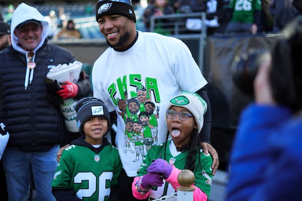 Philadelphia Eagles running back Saquon Barkley poses for photos with kids before an NFL football game against the New York Giants on Sunday, Jan. 5, 2025, in Philadelphia. (AP Photo/Chris Szagola)