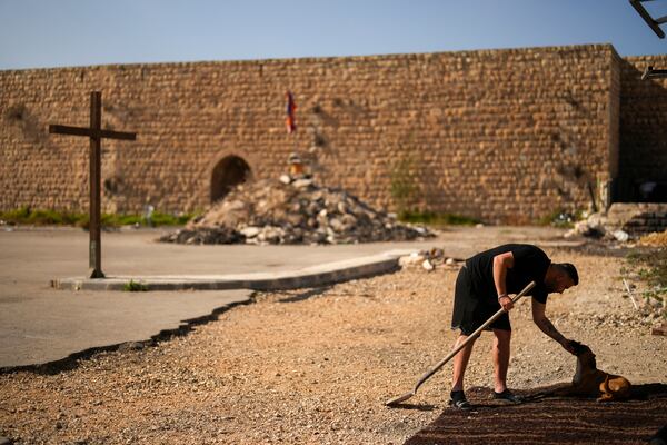 An Armenian activist pets a dog in a parking area known by locals as "Cows garden" at the Armenian quarter in Jerusalem, Thursday, Nov. 21, 2024. (AP Photo/Francisco Seco)