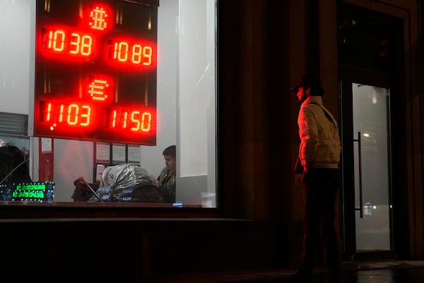 A man watches at an exchange office sign showing the currency exchange rates of the Russian ruble, U.S. dollar, and euro in Moscow, Russia, Thursday, Nov. 28, 2024. (AP Photo/Pavel Bednyakov)