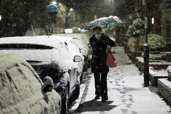 A person walks down a street during snowfall in Warwick, England, Tuesday, Nov. 19, 2024. (Jacob King/PA Wire/PA via AP)