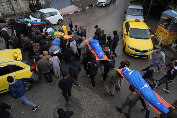 Mourners carry the bodies of four Palestinians killed after there vehicle was targeted by an Israeli airstrike in the refugee camp of Tulkarem on Thursday, one is wrapped with a Hamas flag, during their funeral in the West Bank city of Tulkarem Friday, Dec.20, 2024. (AP Photo/Nasser Nasser)