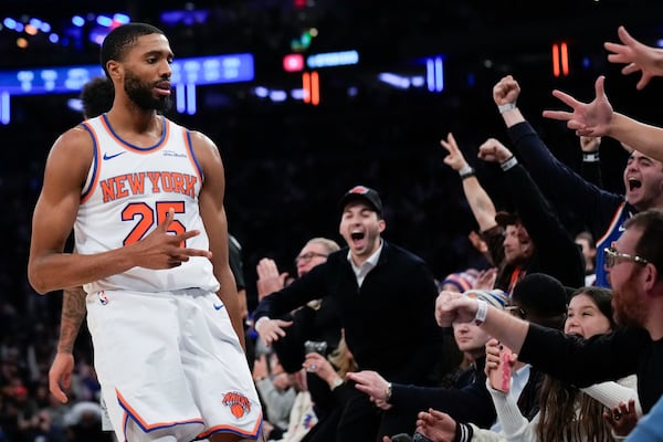 New York Knicks' Mikal Bridges, left, and fans react after Bridges hit a three point basket during the second half of an NBA basketball game, Wednesday, Dec. 25, 2024, in New York. The Knicks defeated the Spurs 117-114. (AP Photo/Seth Wenig)