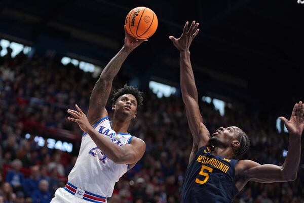 Kansas forward KJ Adams Jr. shoots over West Virginia guard Toby Okani (5) during the first half of an NCAA college basketball game, Tuesday, Dec. 31, 2024, in Lawrence, Kan. (AP Photo/Charlie Riedel)