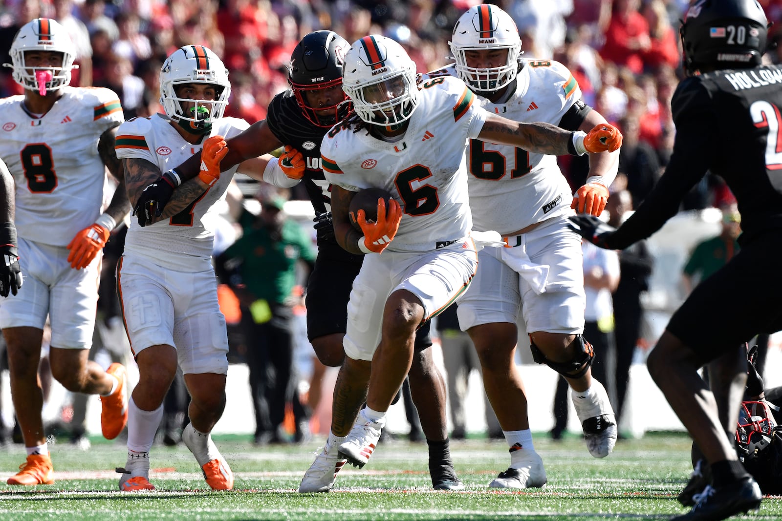 Miami running back Damien Martinez (6) runs through an opening in the Louisville defensive line during the second half of an NCAA college football game in Louisville, Ky., Saturday, Oct. 19, 2024. (AP Photo/Timothy D. Easley)