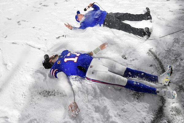 Buffalo Bills quarterback Josh Allen (17) and head coach Sean McDermott make snow angels on the field while being interviewed after an NFL football game against the San Francisco 49ers in Orchard Park, N.Y., Sunday, Dec. 1, 2024. (AP Photo/Adrian Kraus)