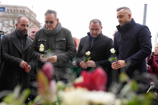 Leader of AfD party Tino Chrupalla, second from right, pays tribute for deaths outside St. John's Church near a Christmas Market, where a car drove into a crowd on Friday evening, in Magdeburg, Germany, Saturday, Dec. 21, 2024. (AP Photo/Ebrahim Noorozi)