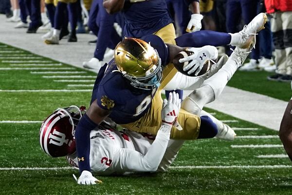 Notre Dame wide receiver Jayden Thomas (83) reaches for yardage after a catch as Indiana linebacker Jailin Walker (2) defends during the second half in the first round of the NCAA College Football Playoff, Friday, Dec. 20, 2024, in South Bend, Ind. (AP Photo/Darron Cummings)