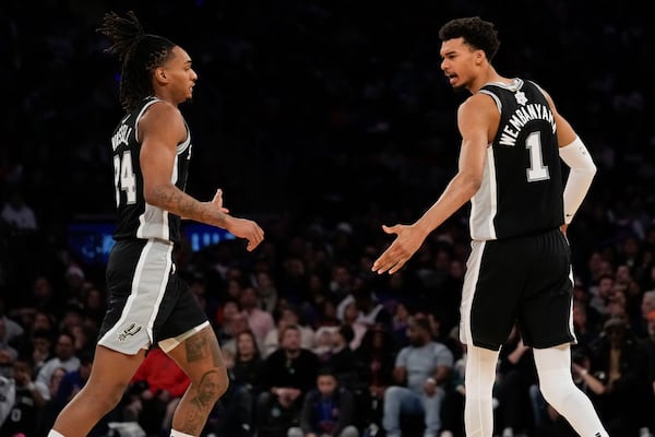 San Antonio Spurs' Victor Wembanyama, right, and Devin Vassell react during the first half of an NBA basketball game against the New York Knicks, Wednesday, Dec. 25, 2024, in New York. (AP Photo/Seth Wenig)