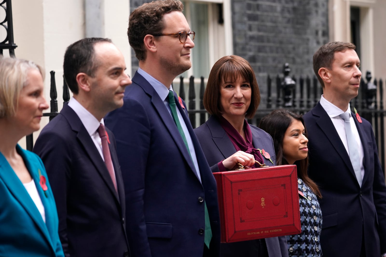 Britain's Chancellor of the Exchequer, Rachel Reeves, holds up the traditional red ministerial box containing her budget speech, as she poses for the media, with her ministerial team outside No 11 Downing Street, before departing to the House of Commons to deliver the budget in London, Wednesday, Oct. 30, 2024. (AP Photo/Alberto Pezzali)