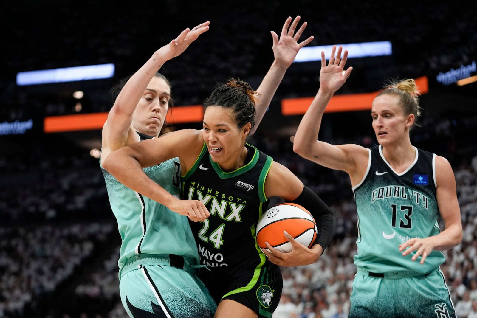 Minnesota Lynx forward Napheesa Collier (24) moves the ball under pressure from New York Liberty forward Breanna Stewart and forward Leonie Fiebich (13) during the second half of Game 4 of a WNBA basketball final playoff series, Friday, Oct. 18, 2024, in Minneapolis. (AP Photo/Abbie Parr)