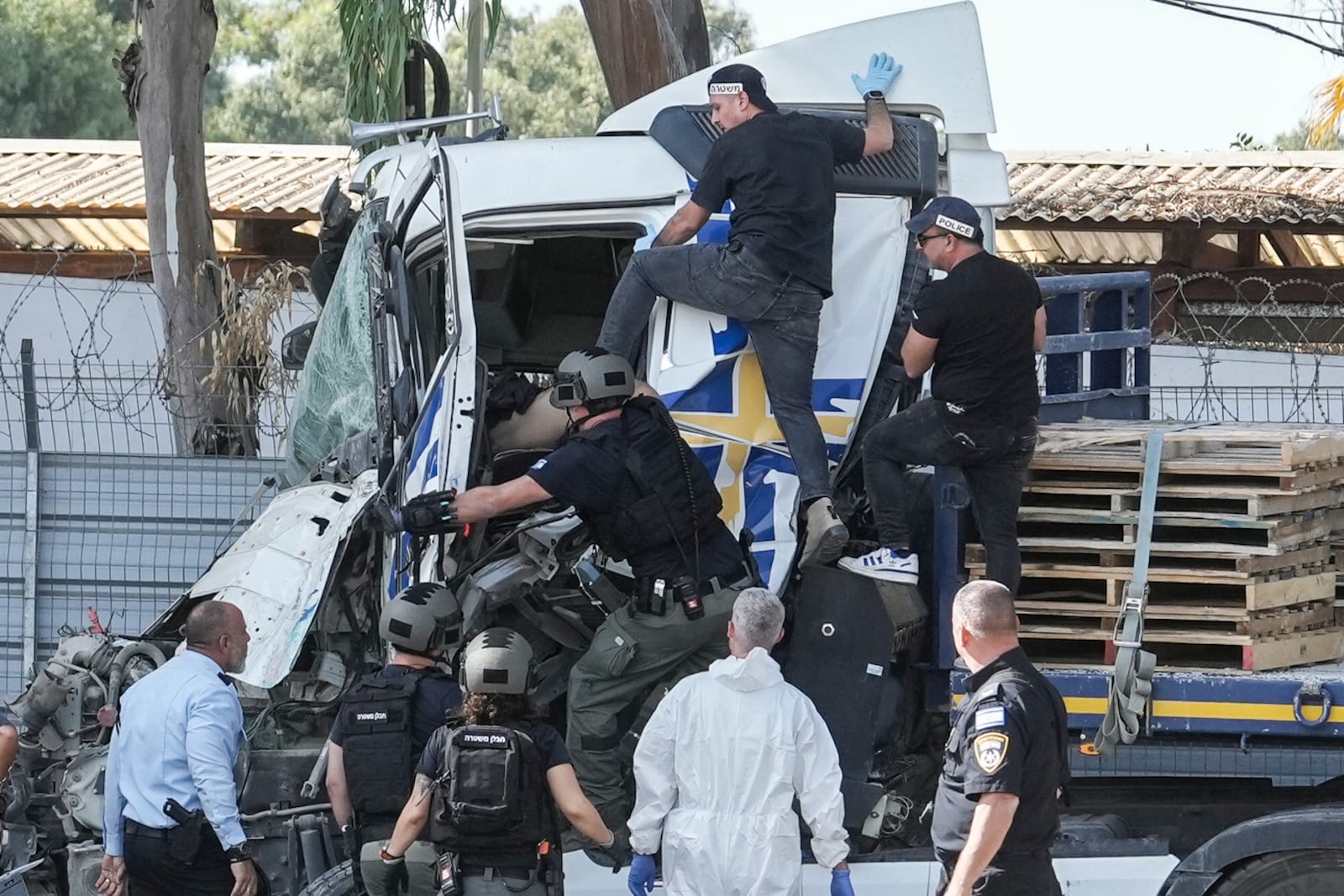 Israeli police climb on a truck to inspect the body of a driver that rammed into a bus stop near the headquarters of Israel's Mossad spy agency, wounding dozens of people, according to Israel's Magen David Adom rescue service in Tel Aviv, Israel, Sunday, Oct. 27, 2024. (AP Photo/Oded Balilty)