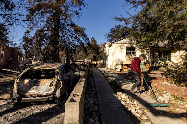 David Slater, right, clears the driveway from his home, spared from the Eaton Fire, Sunday, Jan. 12, 2025 in Altadena, Calif. (AP Photo/Ethan Swope)