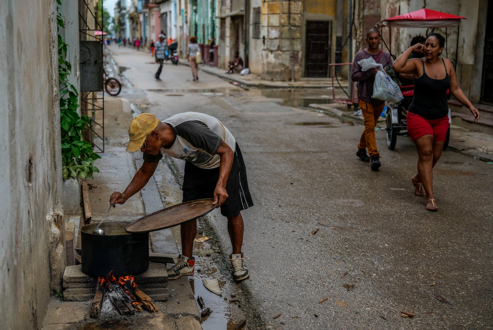 A resident prepares a soup over an open fire during a massive blackout following the failure of a major power plant in Havana, Cuba, Saturday, Oct. 19, 2024. (AP Photo/Ramon Espinosa)