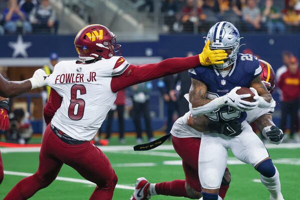 Dallas Cowboys running back Rico Dowdle (23) is stopped by Washington Commanders linebacker Dante Fowler Jr. (6) an linebacker Frankie Luvu, back, during the second half of an NFL football game, Sunday, Jan. 5, 2025, in Arlington, Texas. (AP Photo/Gareth Patterson)