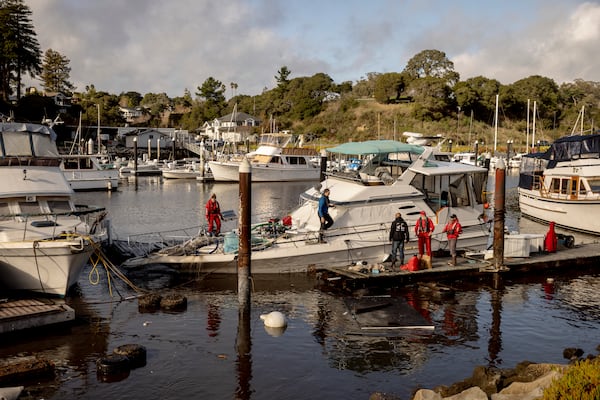 Recovery crews pump water from a semi-submerged boat in Santa Cruz Harbor after it was damaged during high surf in Santa Cruz, Calif., Tuesday, Dec. 24, 2024. (Santa Cruz/San Francisco Chronicle via AP)