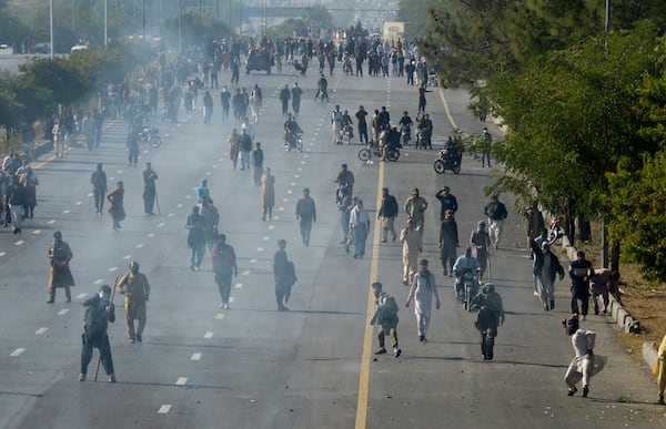 Supporters of imprisoned former premier Imran Khan's Pakistan Tehreek-e-Insaf party, throw stones as police fire tear gas shell to disperse them during clashes, in Islamabad, Pakistan, Tuesday, Nov. 26, 2024. (AP Photo/Irtisham Ahmed)