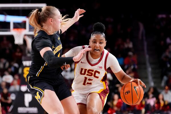 Southern California guard JuJu Watkins, right, drives against Michigan guard Olivia Olson during the second half of an NCAA college basketball game, Sunday, Dec. 29, 2024, in Los Angeles. (AP Photo/Mark J. Terrill)