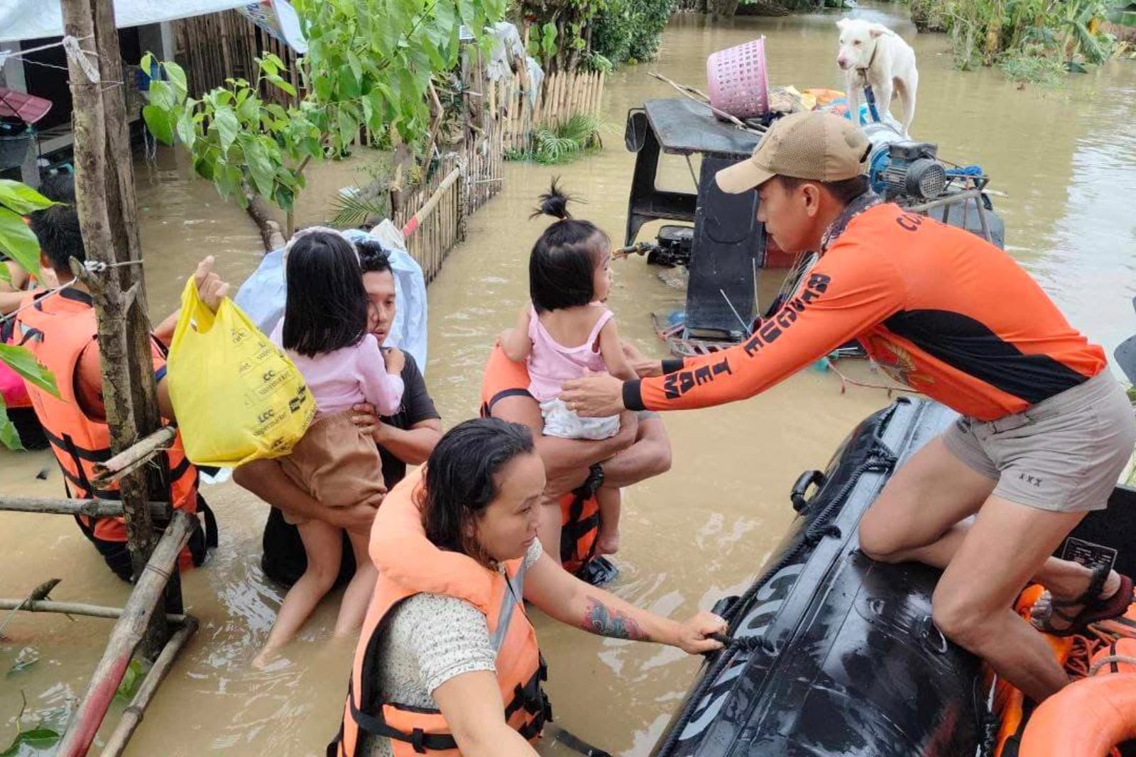 In this handout photo provided by the Philippine Coast Guard, rescuers carry residents trapped in their home after floods caused by Tropical Storm Trami, locally named Kristine, hit their village at Libon, Albay province, Philippines on Wednesday, Oct. 23, 2024. (Philippine Coast Guard via AP)