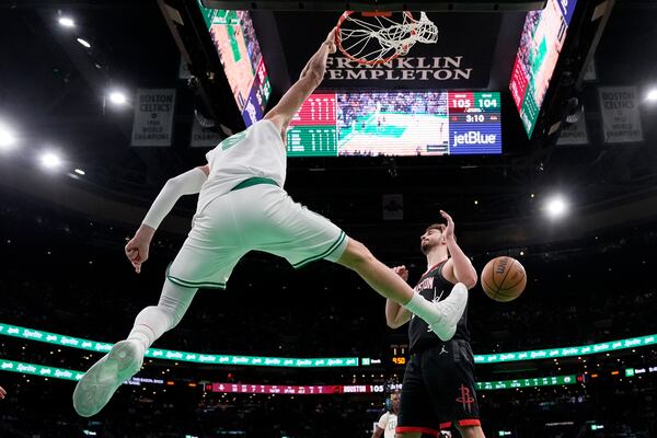 Boston Celtics center Kristaps Porzingis (8) slams a dunk over Houston Rockets center Alperen Sengun, right, during the second half of an NBA basketball game, Monday, Jan. 27, 2025, in Boston. (AP Photo/Charles Krupa)