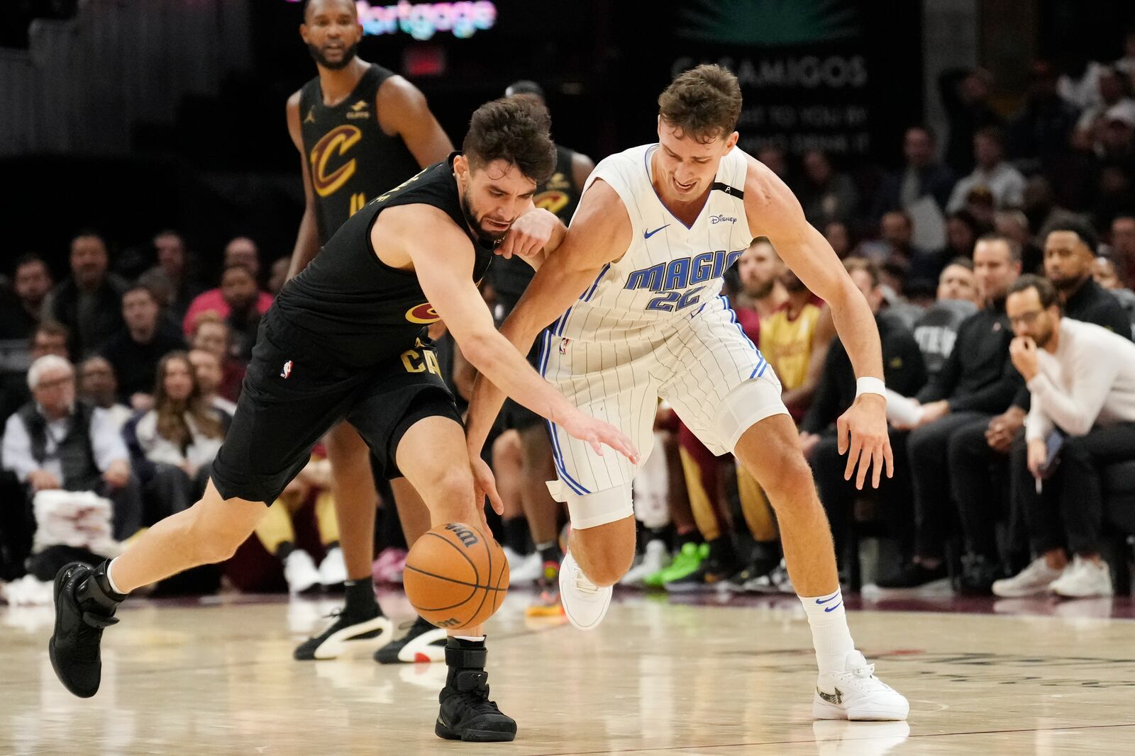 Cleveland Cavaliers guard Ty Jerome, left, and Orlando Magic forward Franz Wagner, right, reach for a loose ball in the first half of an NBA basketball game, Friday, Nov. 1, 2024, in Cleveland. (AP PhotoSue Ogrocki)