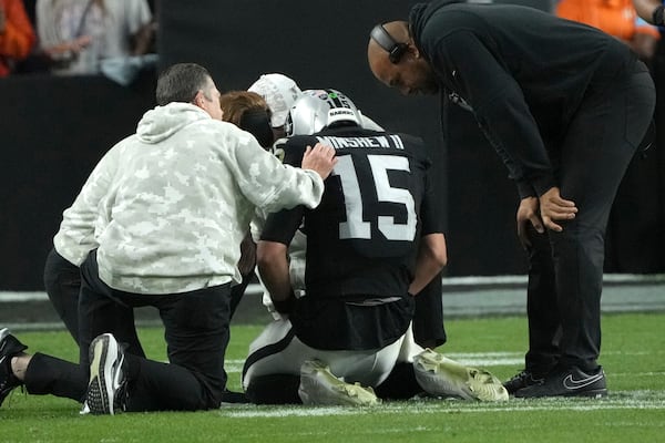 Las Vegas Raiders quarterback Gardner Minshew (15) is assisted by trainers and Head Coach Antonio Pierce, right, after an injury during the second half of an NFL football game against the Denver Broncos, Sunday, Nov. 24, 2024, in Las Vegas. (AP Photo/Rick Scuteri)