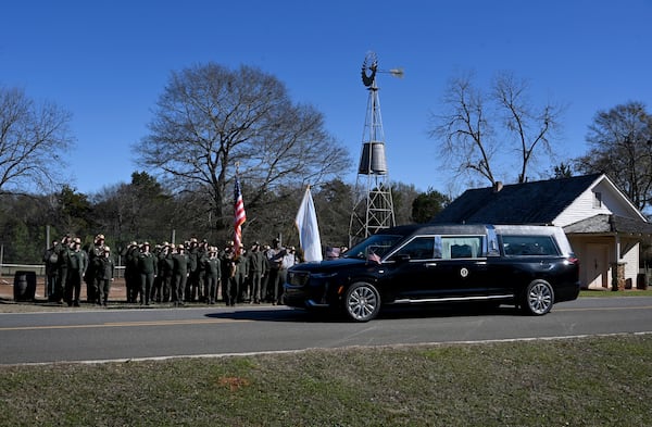 NPS employees, based out of Sumter County, Ga., salute the hearse carrying the flag-draped casket of former President Jimmy Carter as the motorcade stops in front of the Boyhood Farm, where President Carter grew up, Saturday, Jan. 4, 2025, in Plains, Ga. (Hyosub Shin/Atlanta Journal-Constitution via AP, Pool)