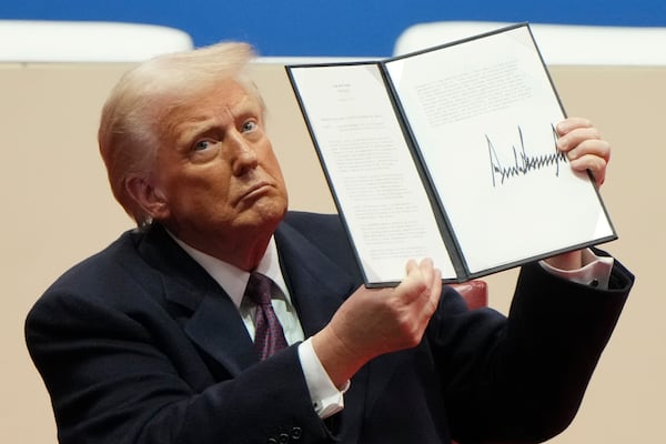 President Donald Trump holds up an executive orders after signing it at an indoor Presidential Inauguration parade event in Washington, Monday, Jan. 20, 2025. (AP Photo/Matt Rourke