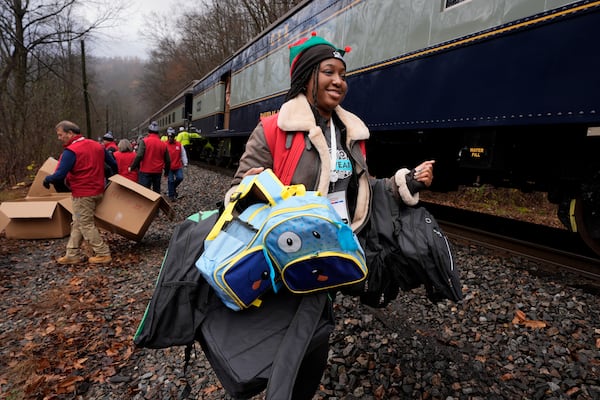 Ilizabeth White delivers gift bags to children during the 82nd run of the CSX Santa Train, Saturday, Nov. 23, 2024, in Fremont, Va. The train brings presents to small towns along a 110-mile portion of the railroad line in rural Appalachian Tennessee, Kentucky and Virginia. (AP Photo/George Walker IV)