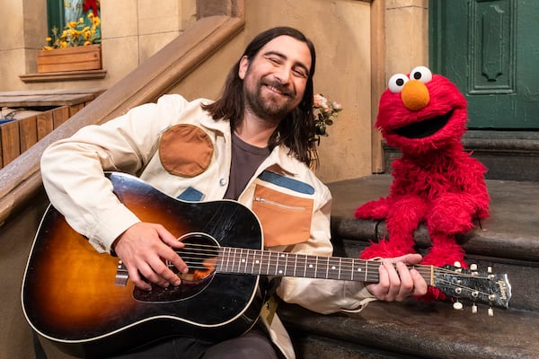 This image released by Sesame Workshop shows singer Noah Kahan, left, with muppet character Elmo on the set of "Sesame Street." (Zach Hyman/Sesame Workshop via AP)