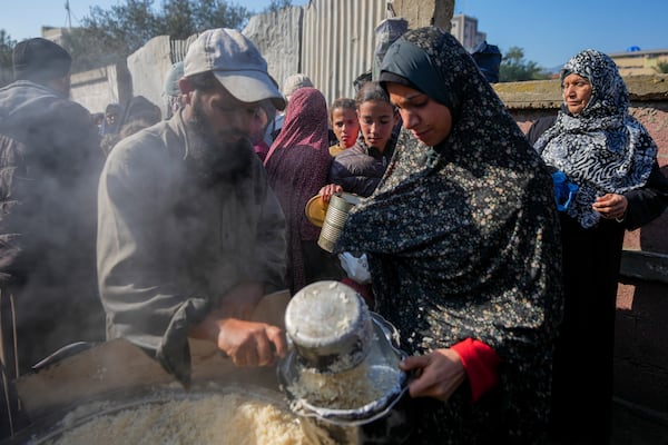 Palestinians collect donated food at a food distribution center in Deir al-Balah, central Gaza Strip, Thursday Jan. 2, 2025. (AP Photo/Abdel Kareem Hana)