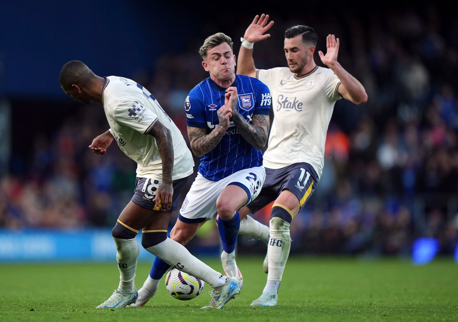 Ipswich Town's Sammie Szmodics is challenged by Everton's Ashley Young, left, and Jack Harrison, right, during the English Premier League soccer match between Ipswich Town and Everton at Portman Road, Ipswich, Saturday Oct. 19, 2024. (Bradley Collyer/PA via AP)