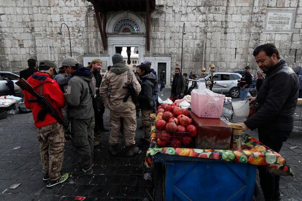 Opposition fighters gather outside the 7th century Umayyad Mosque in Damascus, Syria, Wednesday, Dec. 11, 2024. (AP Photo/Omar Sanadiki)