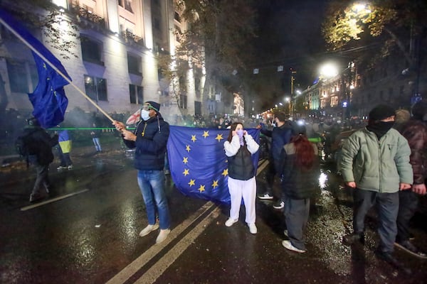 People stand with EU flags following Georgian Prime Minister Irakli Kobakhidze's announcement, rallying outside the parliament building in Tbilisi, Georgia, on Friday, Nov. 29, 2024. (AP Photo/Zurab Tsertsvadze)