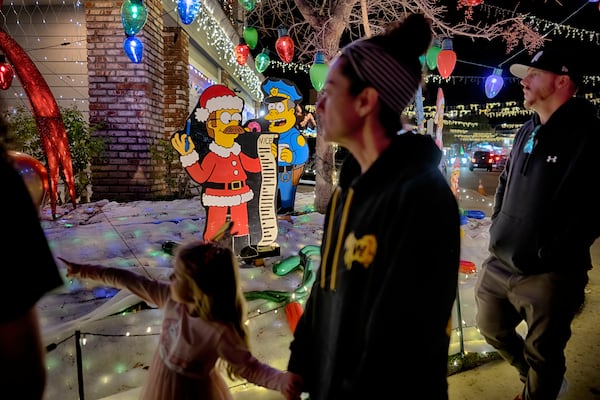 Local residents walk through the Wakefield Winter Wonderland neighborhood decorated with Christmas lights in Santa Clarita, Calif. on Dec. 17, 2024. (AP Photo/Richard Vogel)