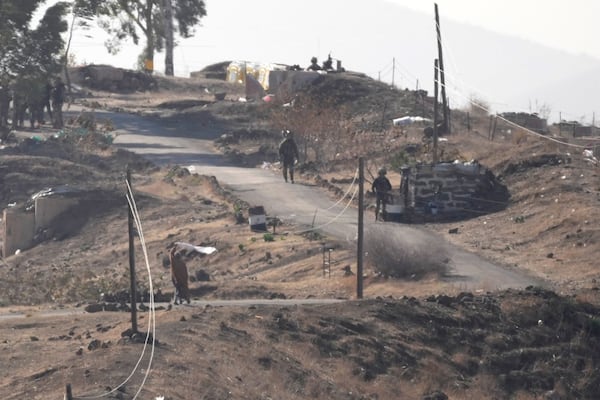 A Syrian man, left, waves a white flag as he approaches Israeli soldiers to negotiate with them, where they set their new position at an abandoned Syrian military base, in Maaryeh village near the border with Israel, in southern Syria, Thursday, Dec. 19, 2024. (AP Photo/Hussein Malla)