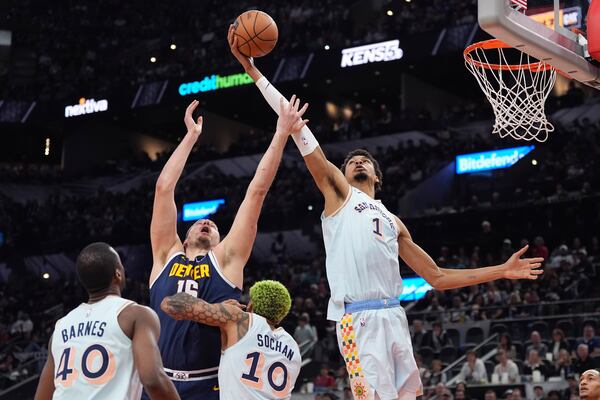 San Antonio Spurs center Victor Wembanyama (1) grabs a rebound over Denver Nuggets center Nikola Jokic (15) during the first half of an NBA basketball game in San Antonio, Saturday, Jan. 4, 2025. (AP Photo/Eric Gay)