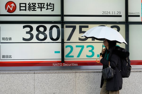 A person walks in front of an electronic stock board showing Japan's Nikkei index at a securities firm Friday, Nov. 29, 2024, in Tokyo. (AP Photo/Eugene Hoshiko)