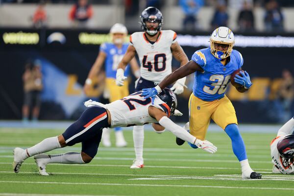 Los Angeles Chargers running back Kimani Vidal (30) is tackled by Denver Broncos safety Brandon Jones (22) during the first half an NFL football game Thursday, Dec. 19, 2024, in Inglewood, Calif. (AP Photo/Ryan Sun)