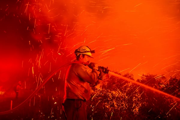 Firefighter Joshua Cari sprays water while battling the Lilac Fire near the Bonsall community of San Diego County, Calif., on Tuesday, Jan. 21, 2025. (AP Photo/Noah Berger)