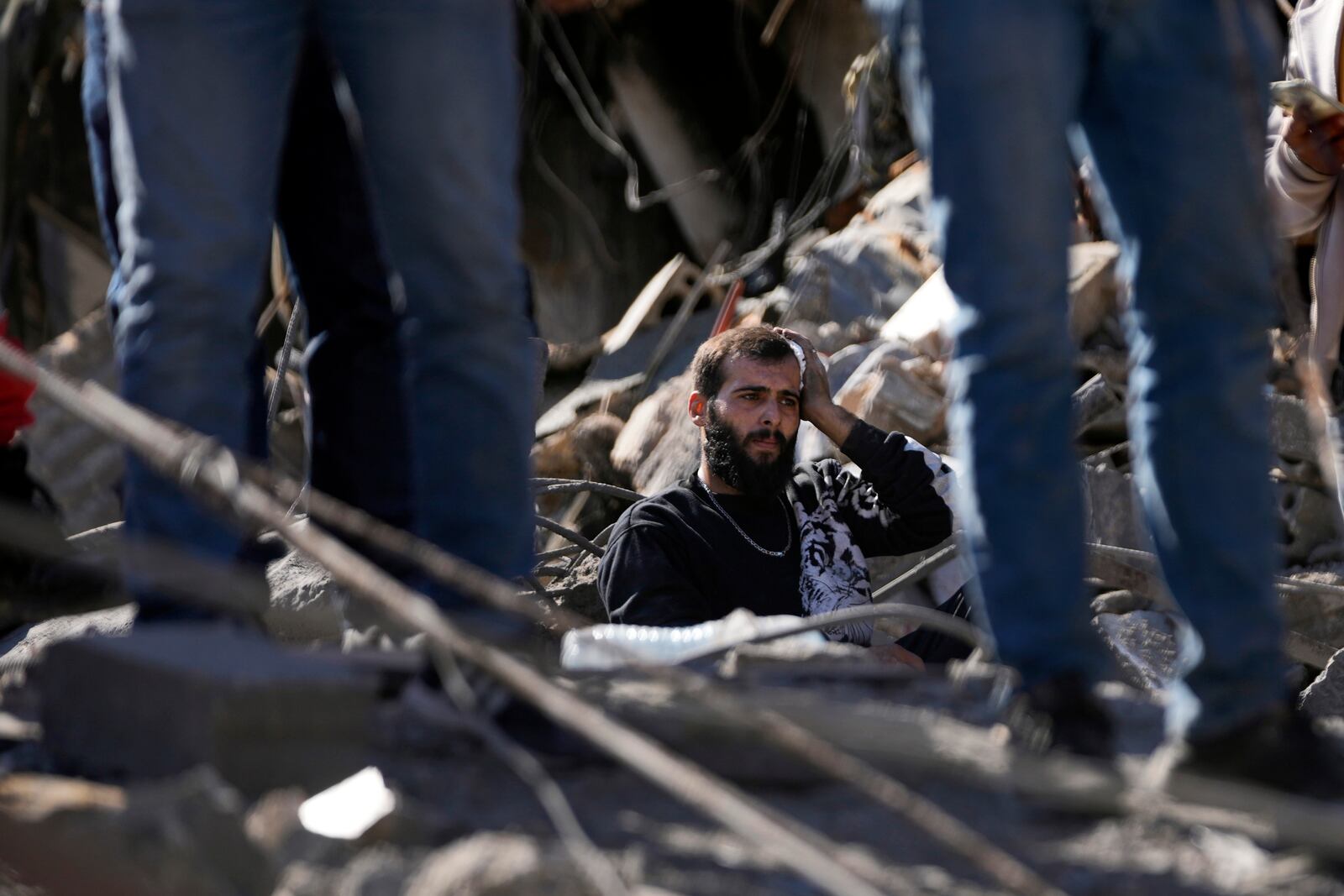 A wounded man pauses in the rubble of destroyed buildings at the site of Israeli airstrikes, facing the city's main government hospital, in southern Beirut, Lebanon, Tuesday, Oct. 22, 2024. (AP Photo/Hussein Malla)