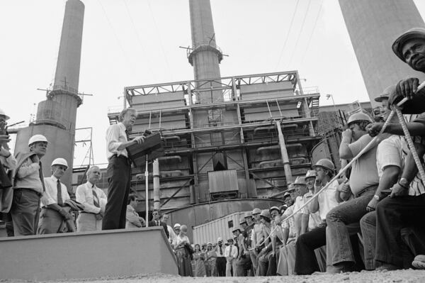 FILE - President Jimmy Carter talks to power plant workers against a backdrop of tall stacks at the Louisville Gas and Electric Company plant in Louisville, Ky., July 31, 1979. (AP Photo, File)