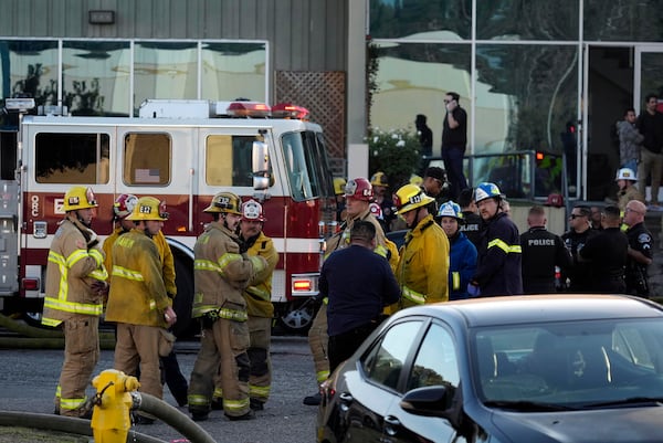 Firefighters respond to a commercial building where a small plane crashed on Thursday, Jan. 2, 2025, in Fullerton, Calif. (AP Photo/Damian Dovarganes)